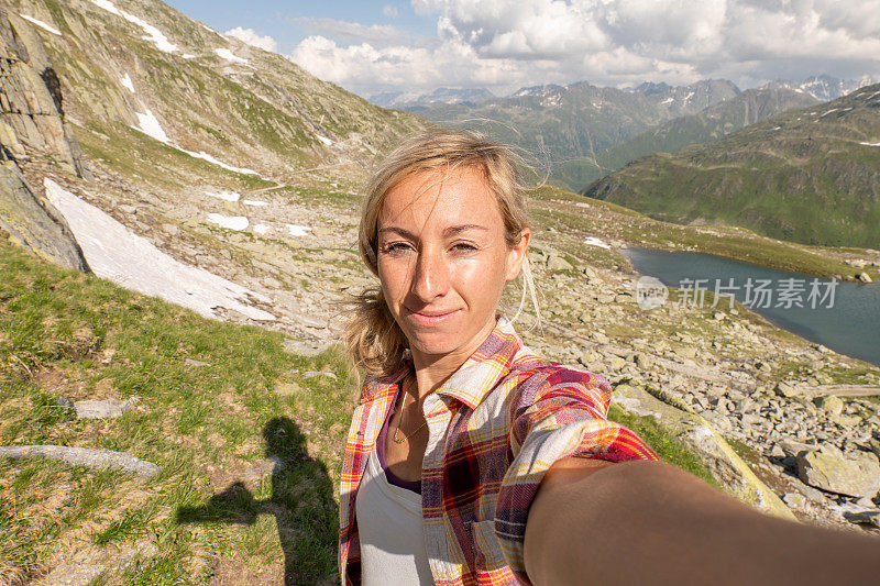 一名女子在瑞士徒步旅行，停下来与全景自拍