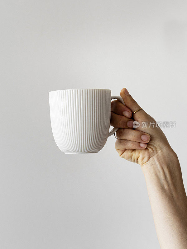 女士的手举起手拿咖啡杯，女士的手拿咖啡杯，新鲜的咖啡杯，手臂举起手拿咖啡杯