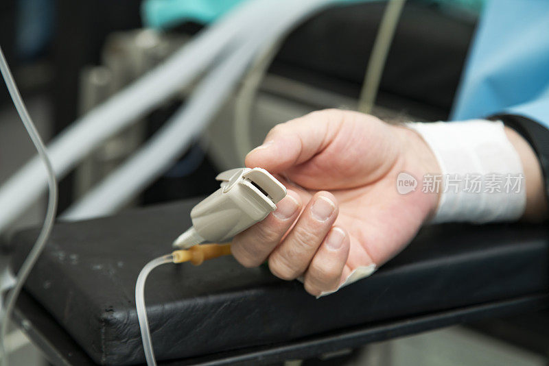 病人躺在手术台上，手上拿着脉搏血氧计。