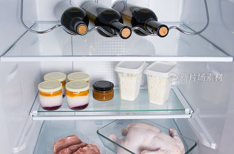 冰箱的货架上放着食物、三瓶葡萄酒、乳品生物制品、肉、鸡肉和牛排