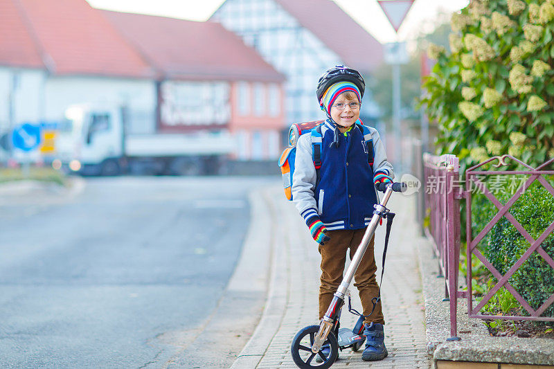 戴着头盔的小男孩骑着滑板车穿过城市