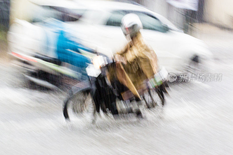 骑摩托车通过雨和洪水与运动模糊