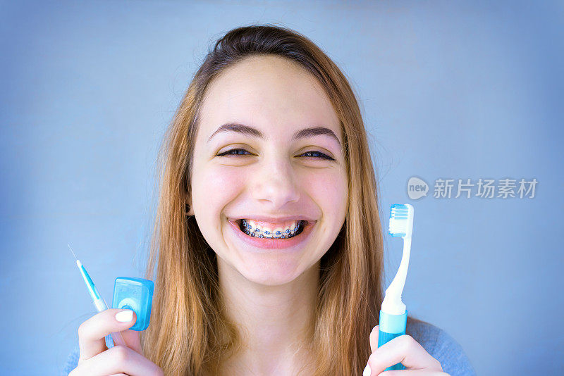 美丽微笑的女孩用牙固位器刷牙。