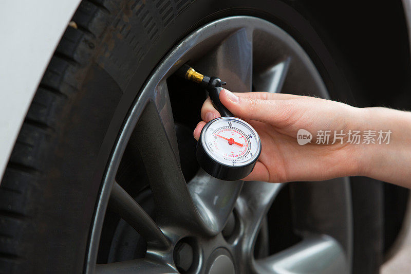 女人用计量器检查汽车轮胎压力的特写