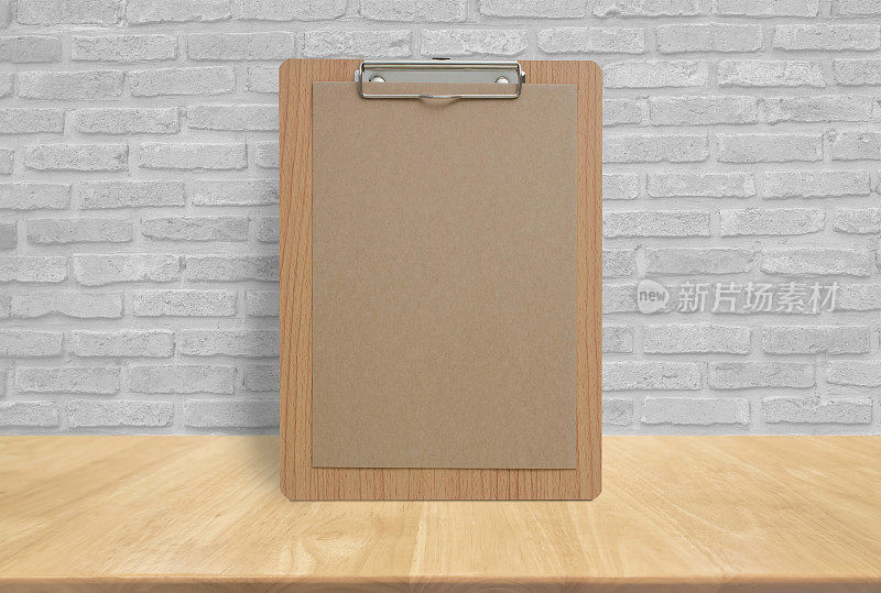 空白的生态纸记事本在砖墙的木制桌面上，模板模拟添加您的设计。