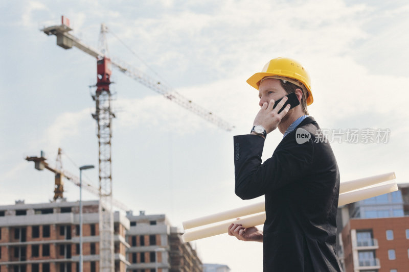 建筑工地的年轻工程师正在用智能手机通话