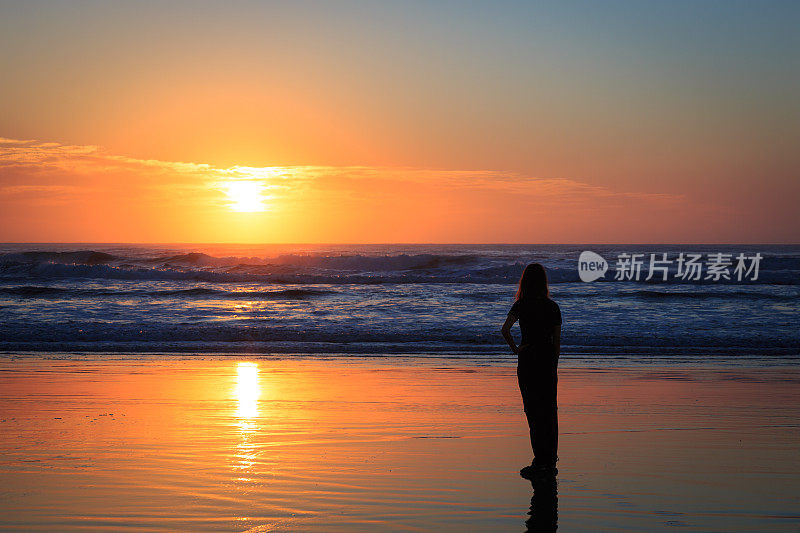 日出时，在热带海滩上的女人剪影