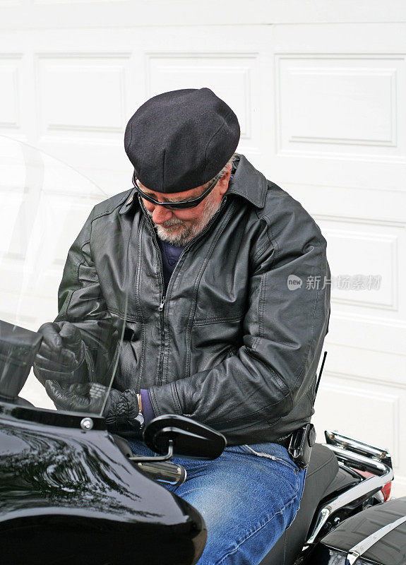 穿着皮夹克坐在摩托车上的男人。