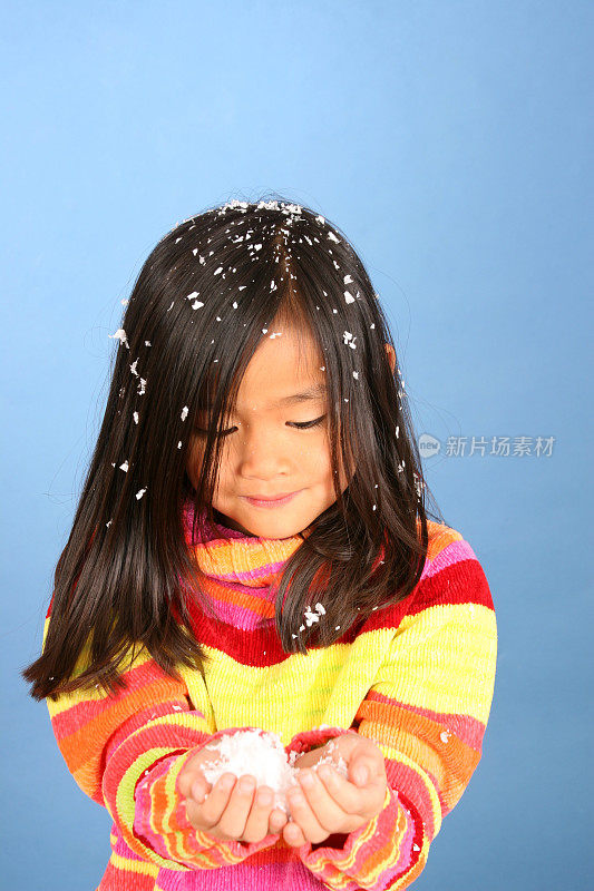 一个中国小女孩看着她满手的雪