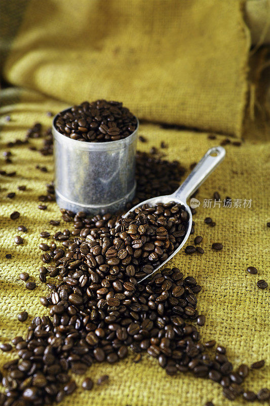 粗麻袋和金属量具的新鲜咖啡豆。