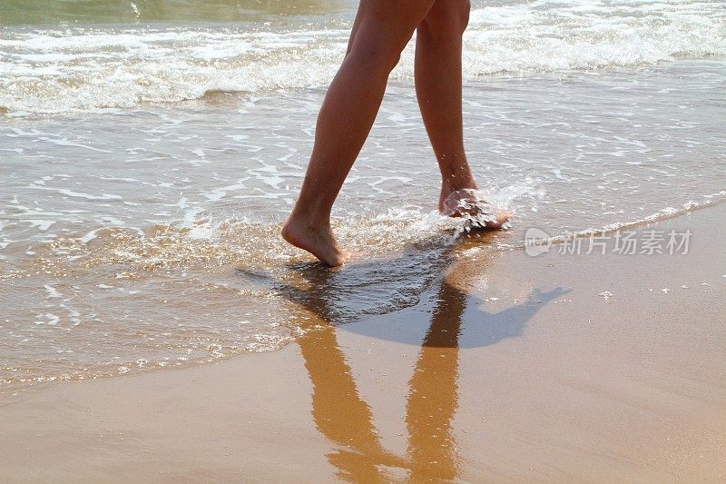 两脚踩在海滩浅水上