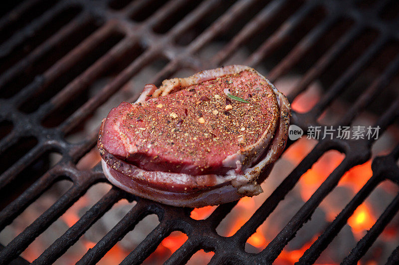 培根包牛肉菲力牛排在燃烧的木炭烤架上