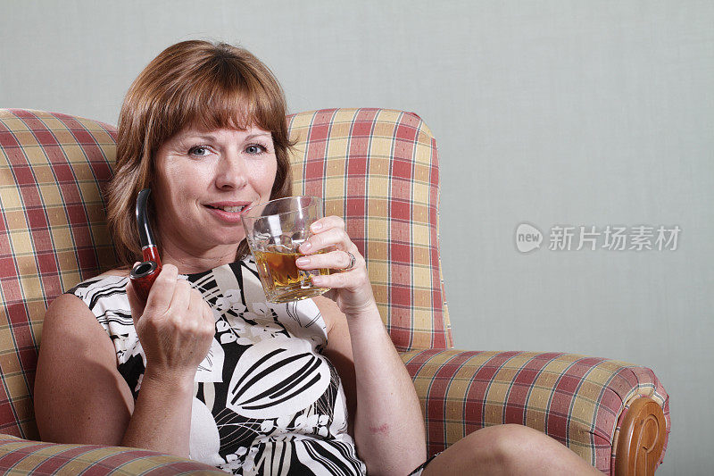 成熟的黑发女人放松在家里烟斗喝酒