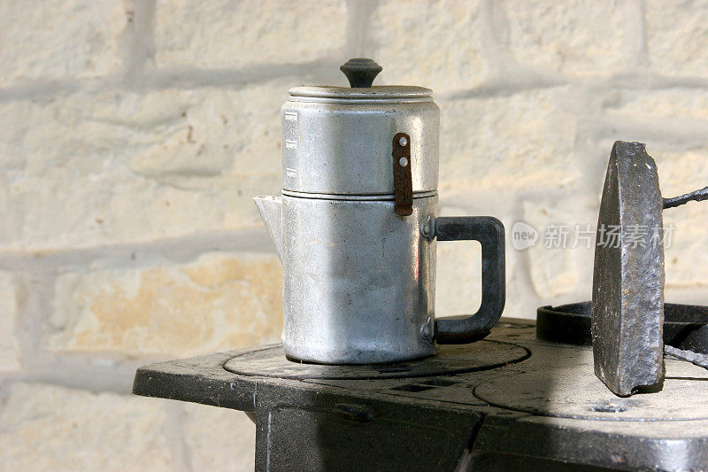 旧铝咖啡壶和铁在迷你炉上。