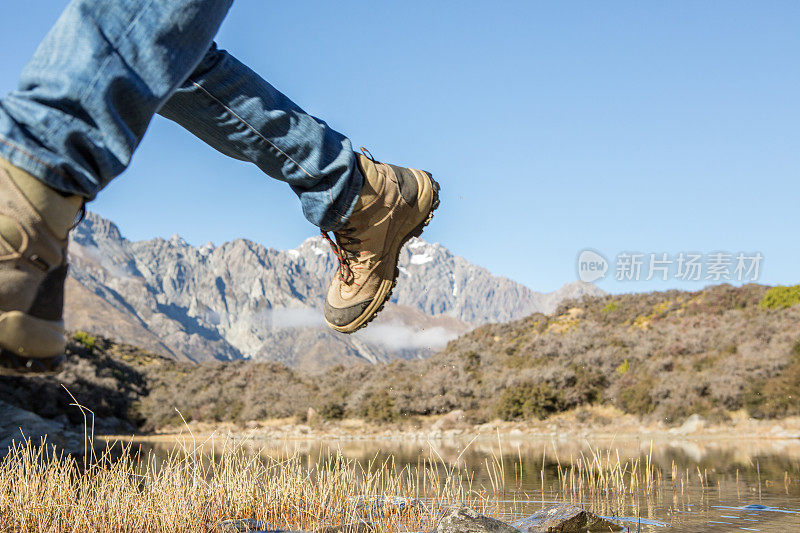 徒步旅行者在山上的湖里从一块岩石跳到另一块岩石上