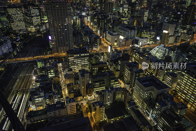 从空中俯瞰霓虹灯闪烁的夜晚城市拥挤的摩天大楼发光的街道