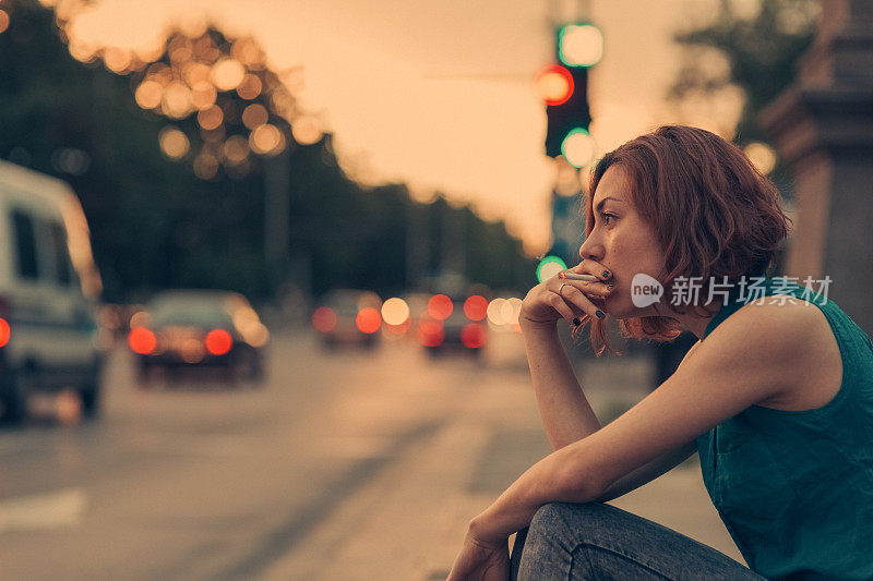沮丧的年轻女子在街上抽烟