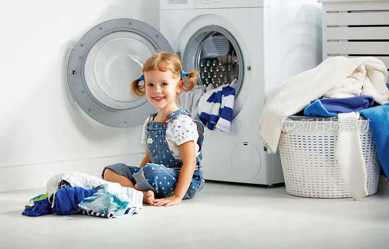 孩子开心快乐的小女孩在洗衣房洗衣服