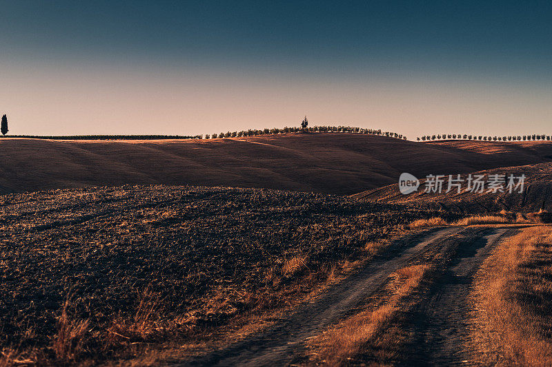 日落时蜿蜒穿过托斯卡纳的道路。意大利。