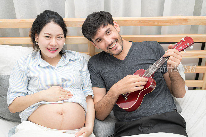 一个美丽快乐的大肚子的孕妇享受听音乐的孩子的特写。怀孕与母性时刻的人与期望概念