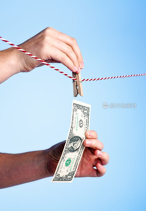 女性手把一美元钞票钉在晾衣绳上