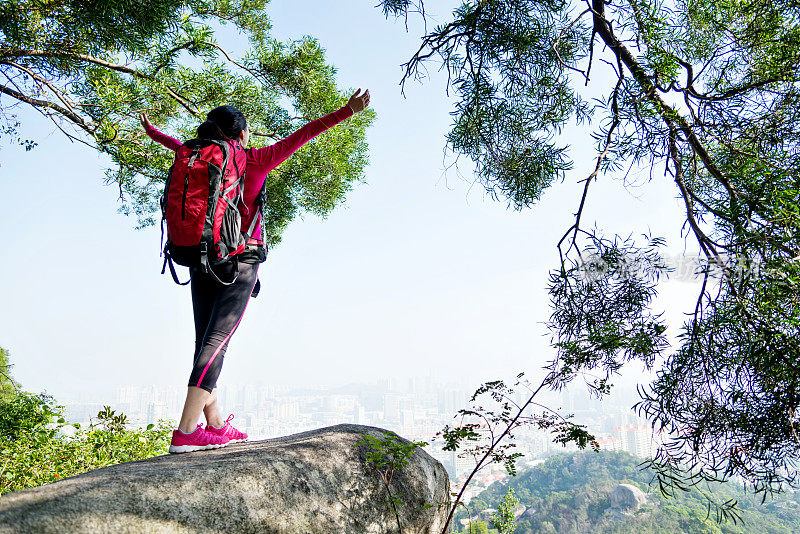 女人站在山顶，双臂举起