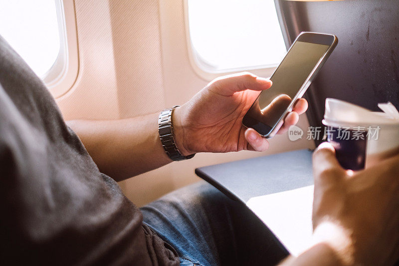 一名年轻人在飞机上用手机发短信