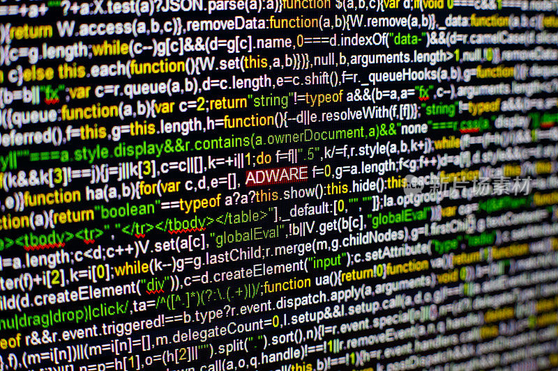 电脑屏幕的微距照片与程序源代码和突出的ADWARE铭文在中间。带有病毒的屏幕上的脚本。网络安全的概念。技术背景