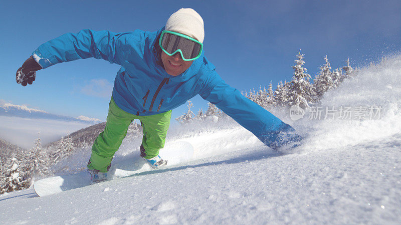 肖像:欢快的男性滑雪板拖动他的手通过新落的雪。