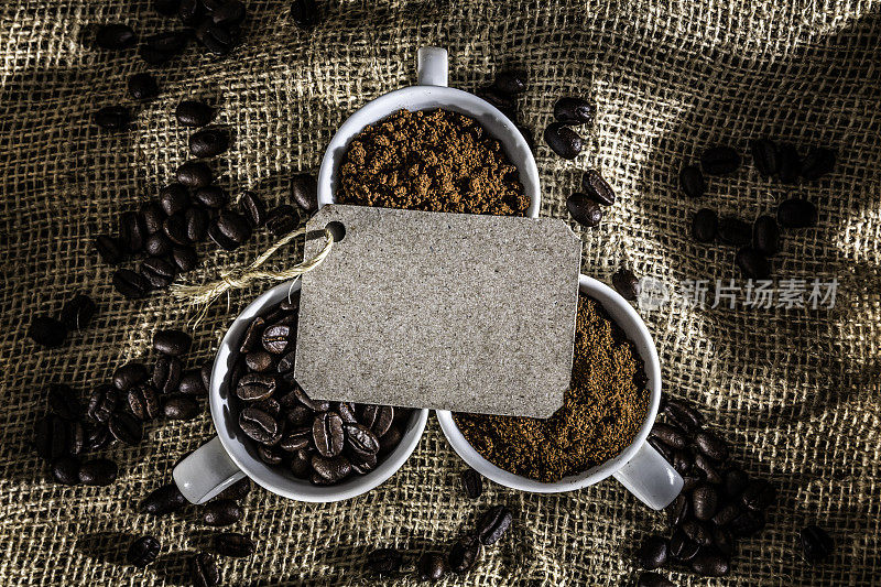 三杯咖啡豆，速溶咖啡和研磨咖啡在黄麻框架与空白标签的拷贝空间