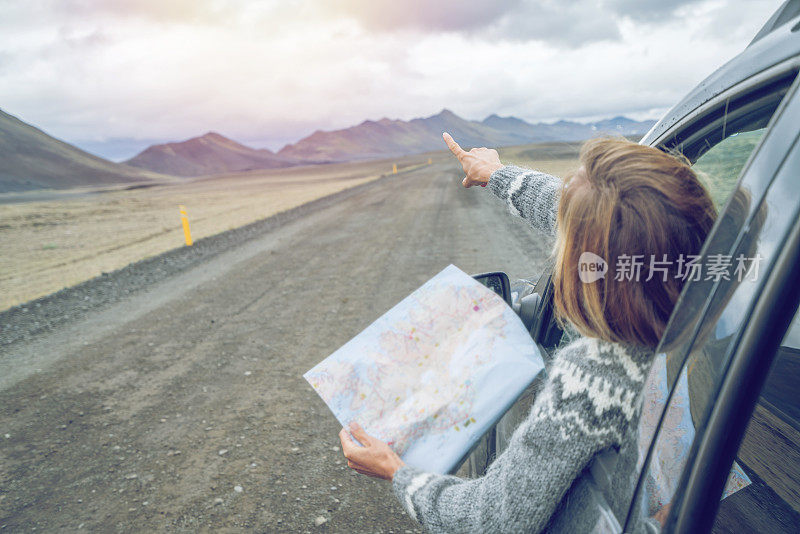 年轻女子在车里看地图，公路旅行的概念假期