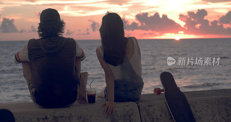 一对年轻的滑冰夫妇边看日落边聊天。