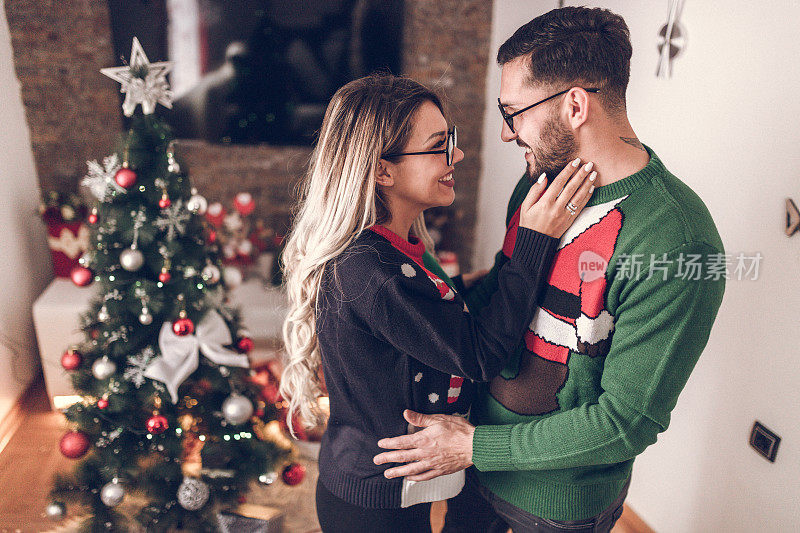 一对年轻情侣在圣诞树旁接吻