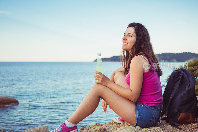 年轻女子在海边喝苏打水