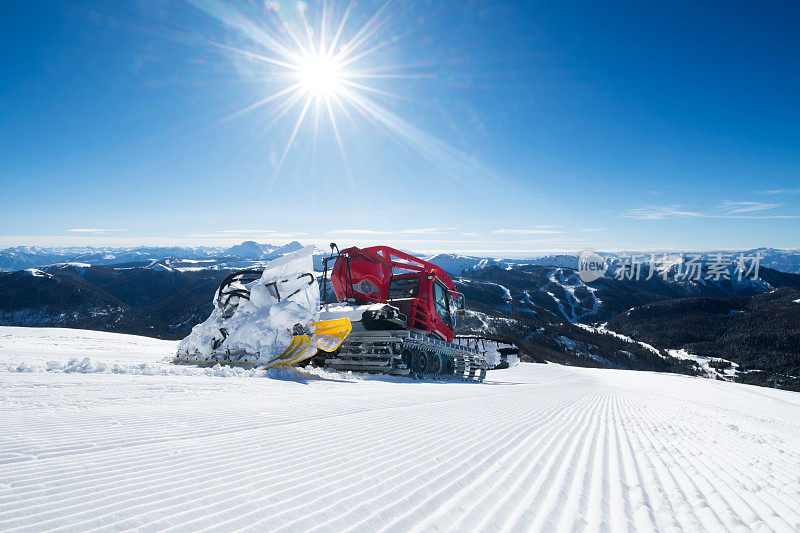 现代红色雪清理过剩的雪在一个美丽的，阳光明媚的日子在山上滑雪道