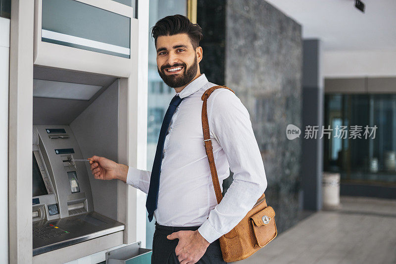 在ATM机上刷卡的商人