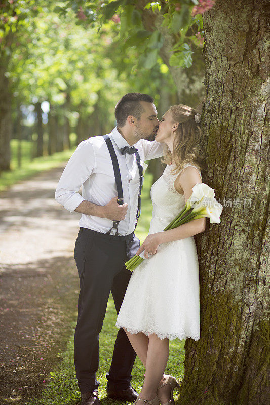 一对新婚夫妇在林荫小道上接吻