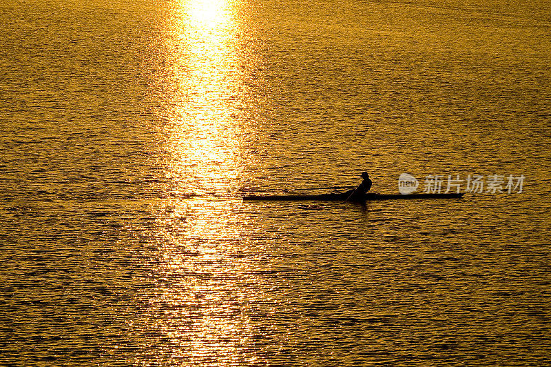 清晨的阳光下，一个男人在波光粼粼的尤多河上划着小船