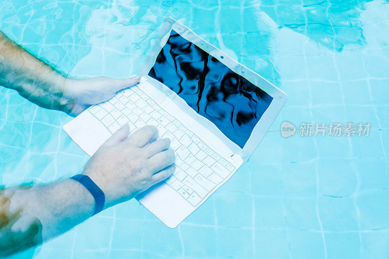 男性的手和一个笔记本电脑在水下工作。阻碍的概念在工作中。模糊抽象的背景