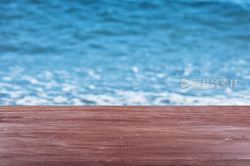 空荡荡的木制桌面上有闪亮的夏日海洋背景