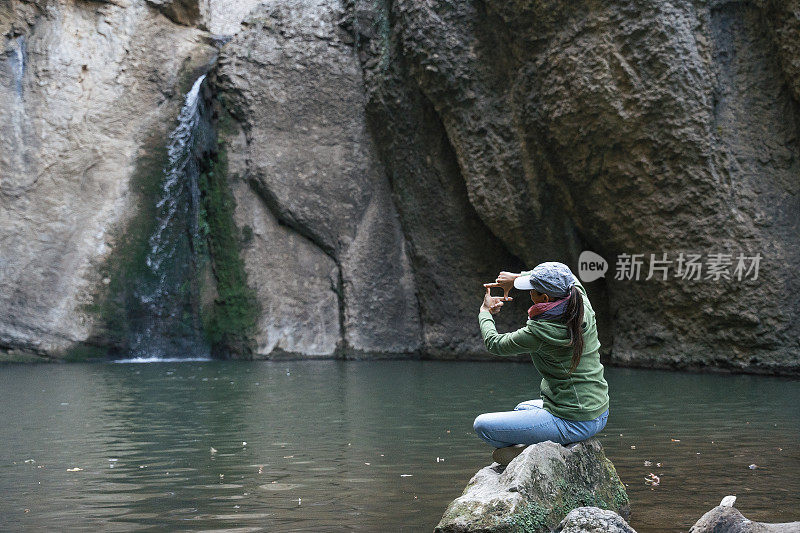 回归自然。独自在瀑布附近旅行。一个快乐的年轻女游客漫步在大自然中。阳光明媚的户外享受。