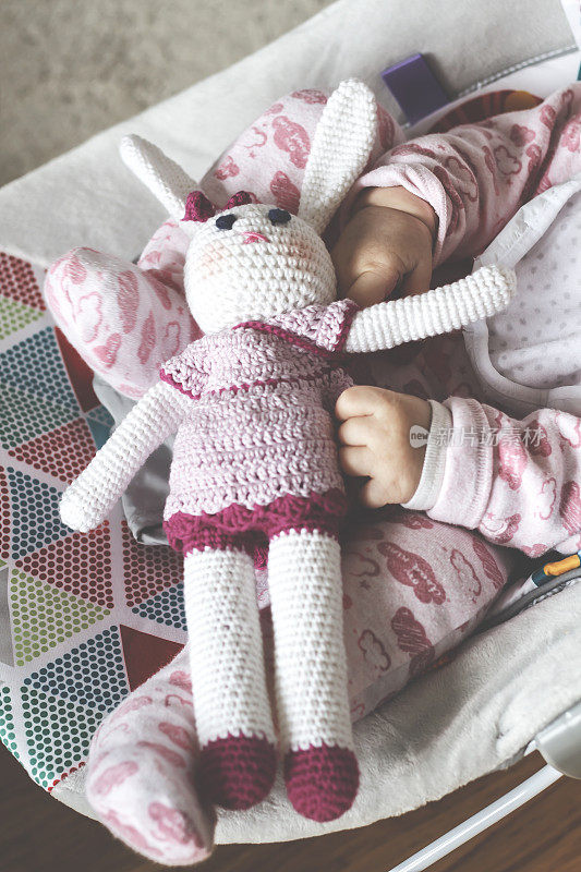 宝宝的手拿着有趣的针织兔子玩具