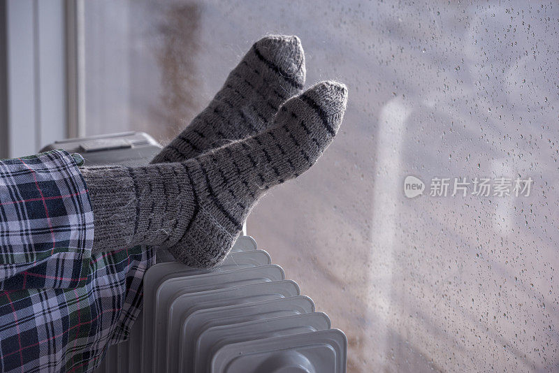 近距离图像的女人的脚散热器加热器在雨季的冬天。