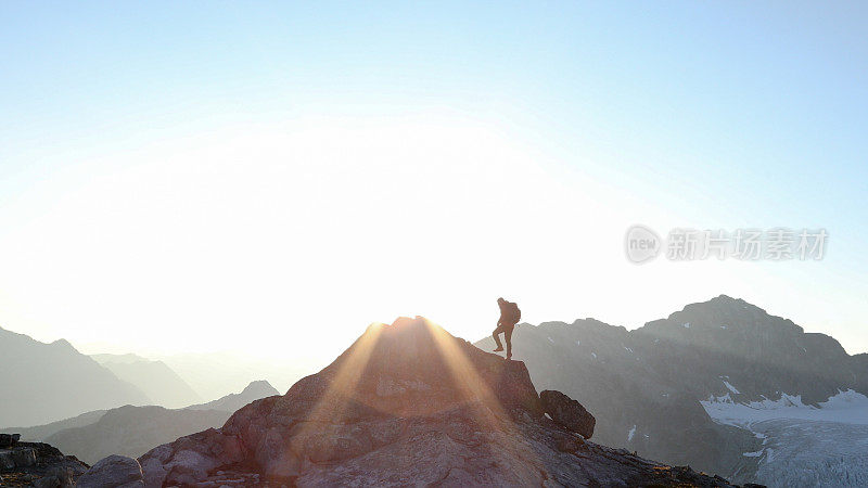 登山运动员在日出时穿过顶峰山脊