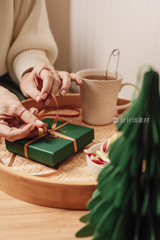 女人一边包装礼物一边喝茶