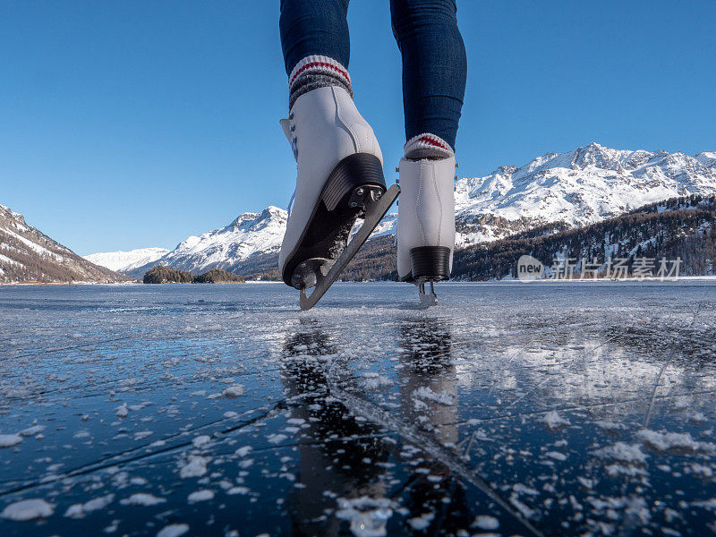 日落时分，在结冰的湖面上穿着溜冰鞋的双脚