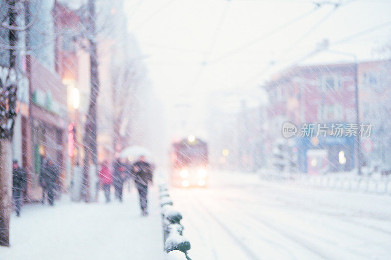 清晨，市中心下着雪，行人在路上行走，背景是有轨电车。