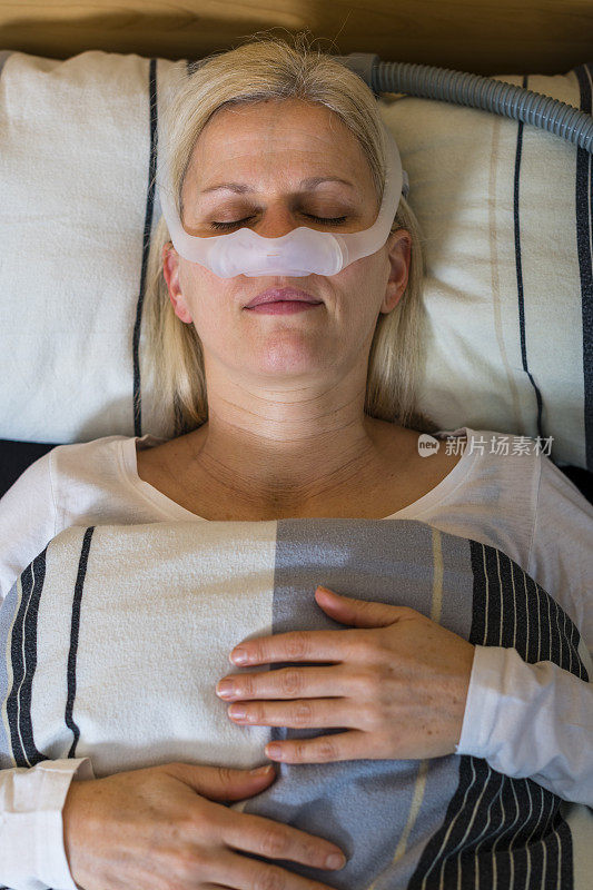 因为阻塞性睡眠呼吸暂停而戴着呼吸面罩睡觉的女人