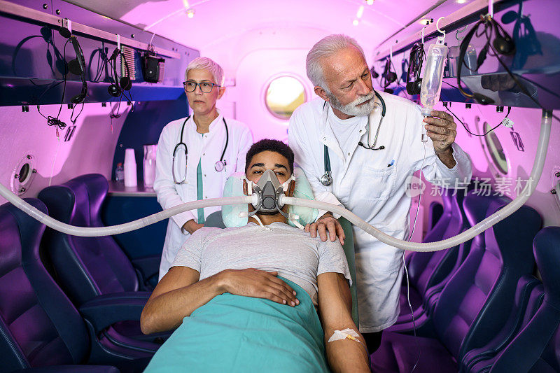 医生为躺着的病人设置呼吸面罩，而护士正在帮助病人准备HBOT治疗
