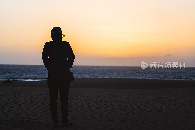 在沙滩上看日出的女人剪影